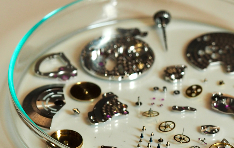 Horlogeonderdelen op de werkbank van een horlogemaker tijdens revisie